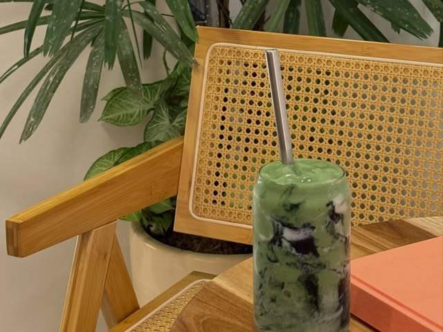Iced matcha in a glass on a rattan table at La Isla Juice Club in Nosara